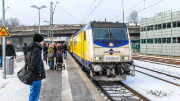 Menschen warten bei Schnee und Eis auf einen Metronom-Zug.