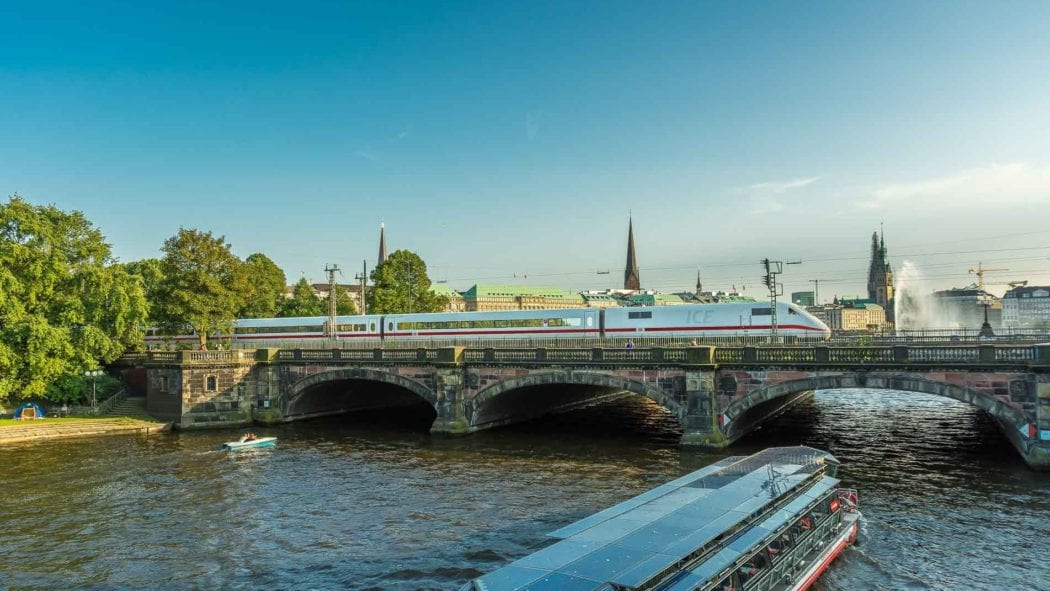 Ein ICE passiert die Lomardsbrücke in Hamburg bei tiefstehender Abendsonne im Sommer