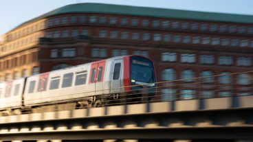 Ein U-Bahn-Zug vom Typ DT5 im goldenen Abendlicht auf einem Viadukt am Baumwall im Hamburger Hafen