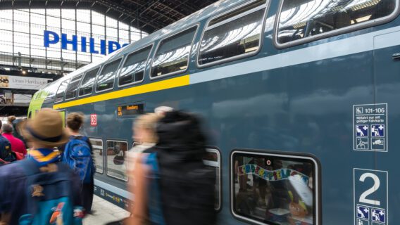 Menschen laufen im Hamburger Hauptbahnhof vor einem Doppelstock-Zug der Deutschen Bahn