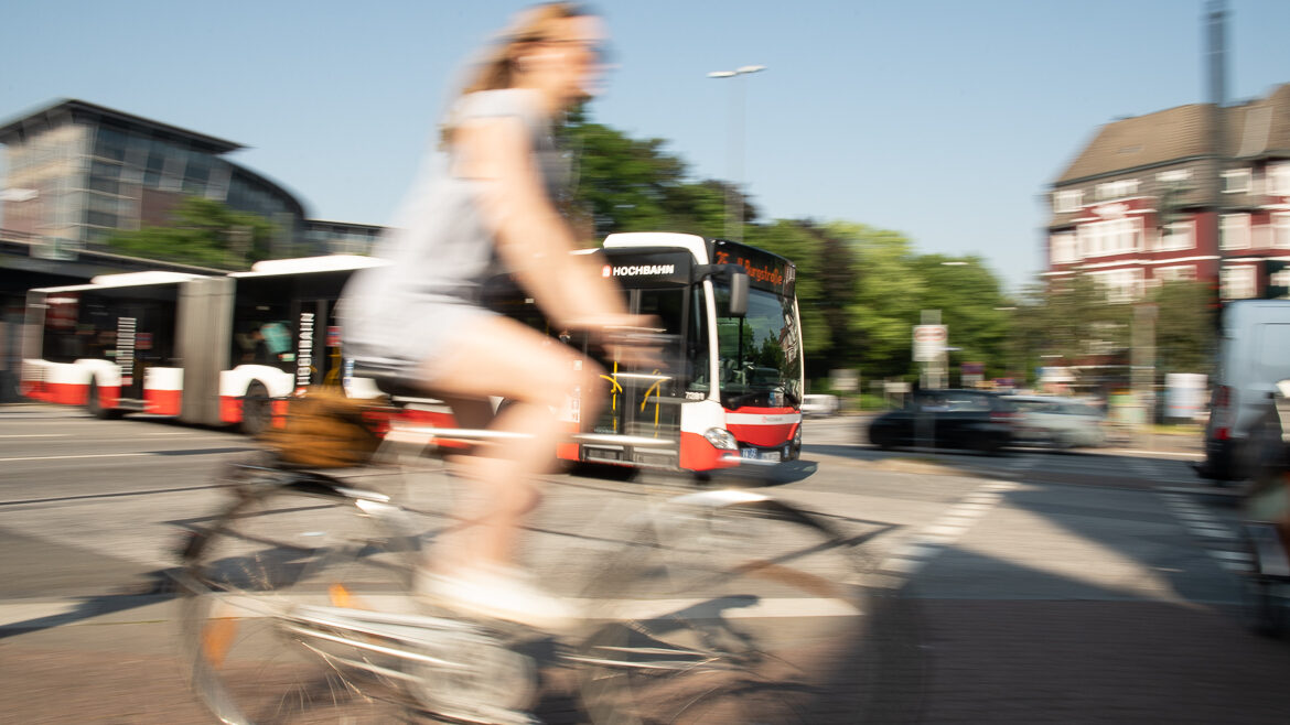 Eine Fahrradfahrerin vor einem Hochbahn-Bus an der Holstenstraße in Hamburg.